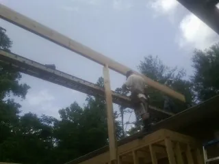 Carpenter setting a ridge beam over a new addition frame — Ice Dam Removal by Roofing Brothers in Albertville