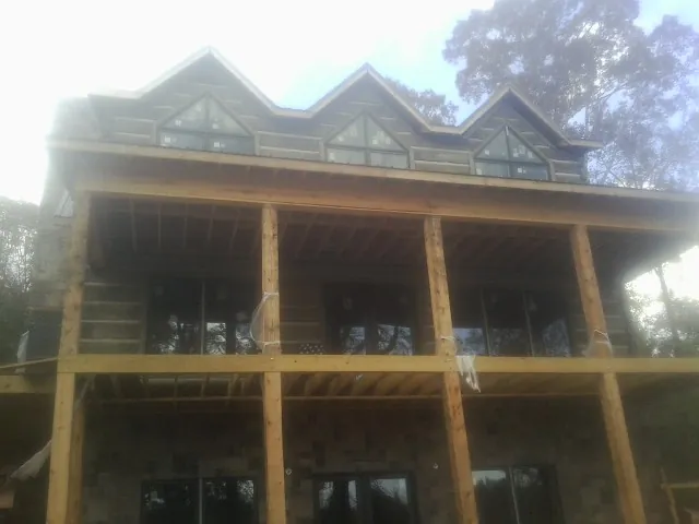 Dormers and porch framing on a large log home under construction — Roof Coating work by our crew in Albertville