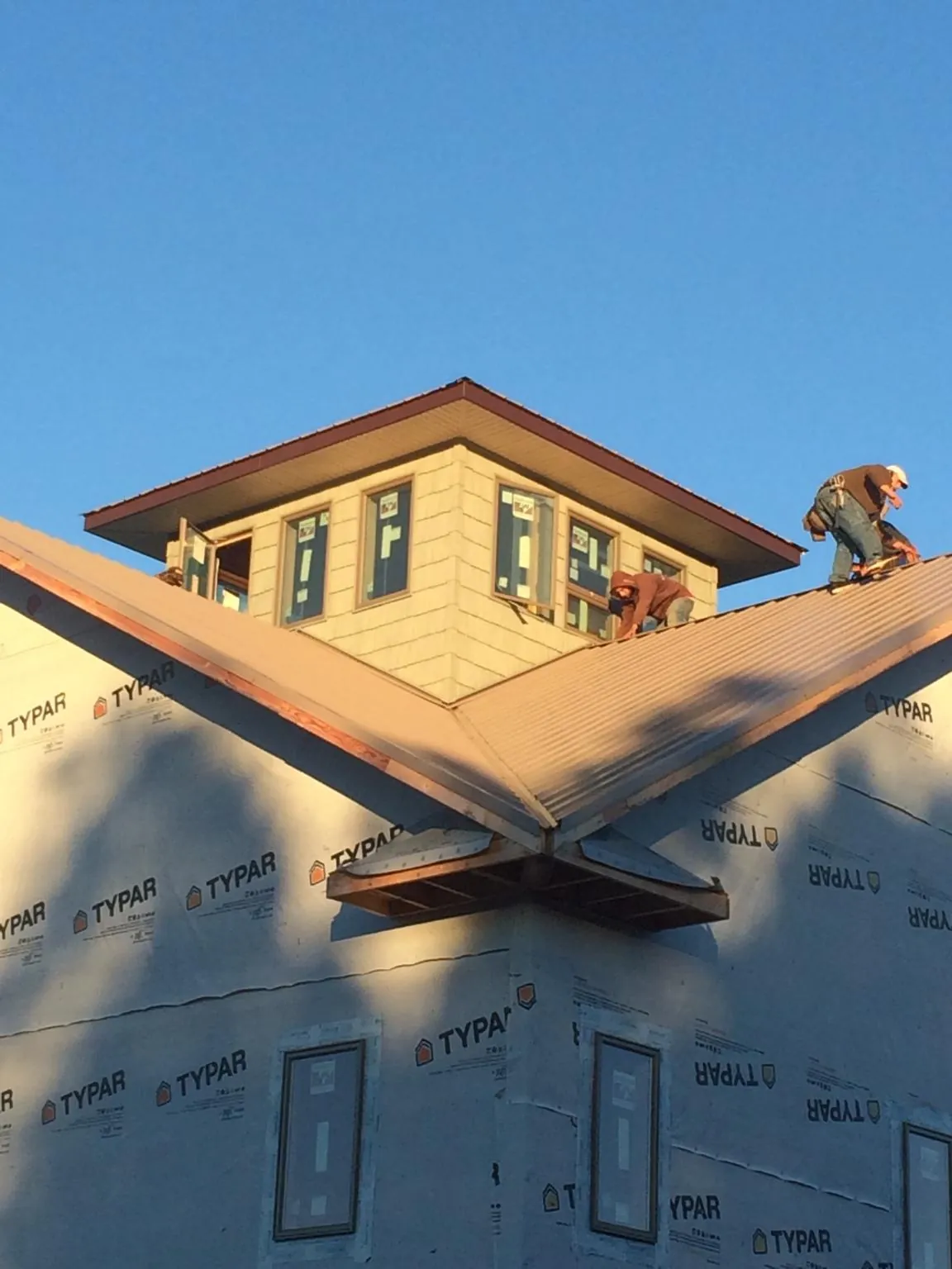 Roofers working around a rooftop cupola on a new metal roof at sunset — Roof Waterproofing in Albertville by Roofing Brothers